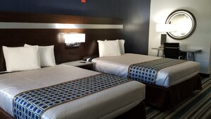 A hotel room with two beds, a nightstand, a lamp, and a mirror.