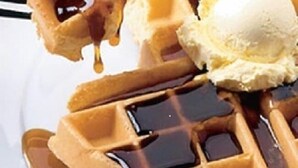 A waffle with syrup and a scoop of ice cream.