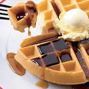 A waffle with syrup and a scoop of ice cream.