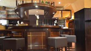 Zona de bar con barra de madera curvada, varios taburetes y un cartel de recepción.