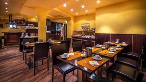 Un restaurante con mesas y sillas de madera, una zona de bar y un bufé.