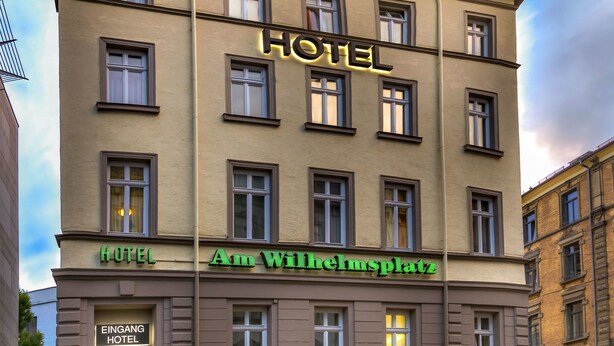Un edificio de hotel con múltiples ventanas y un letrero que dice "HOTEL Am Wilhelmplatz".