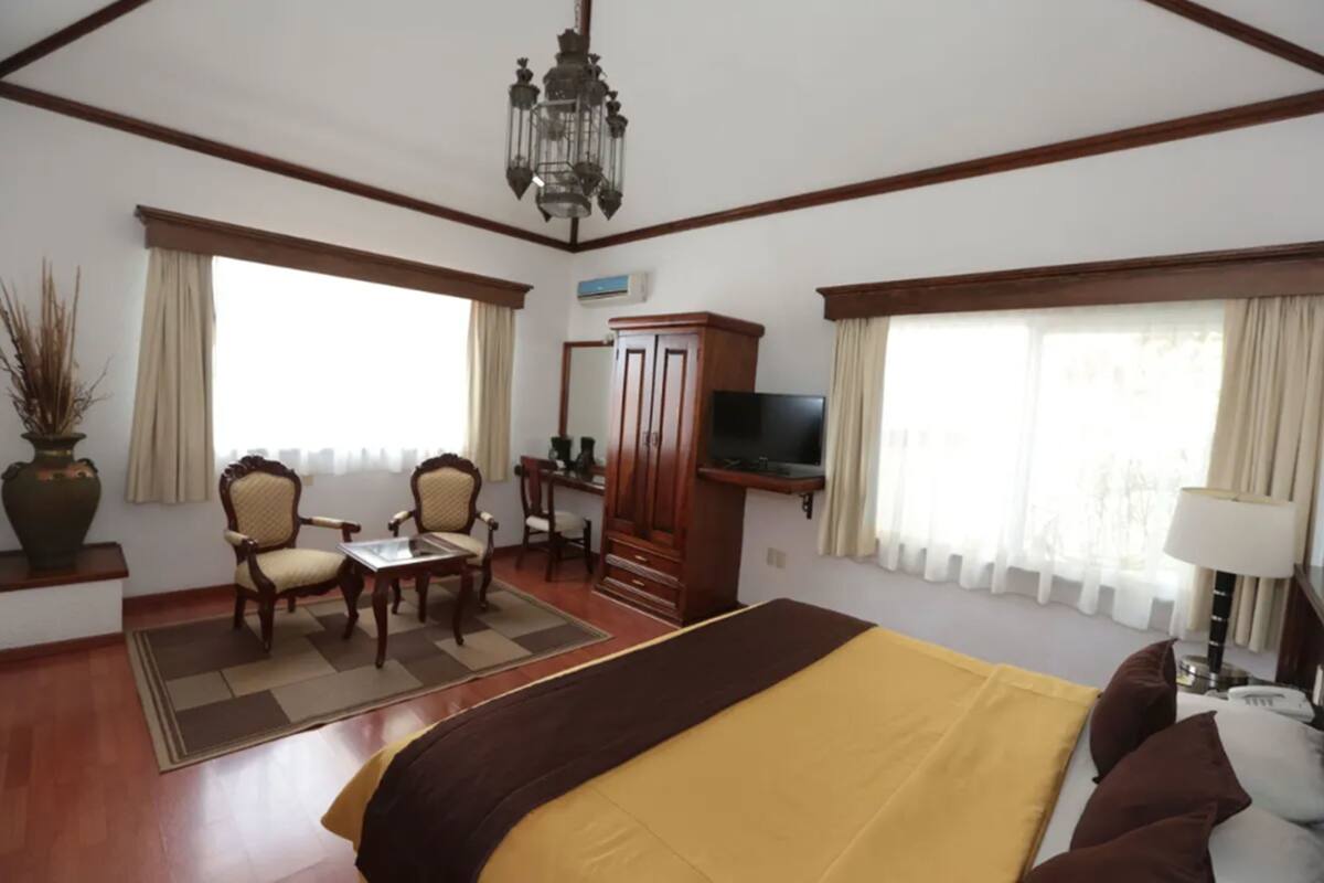 Une chambre d’hôtel avec un grand lit, un bureau avec une chaise, une télévision et un placard.