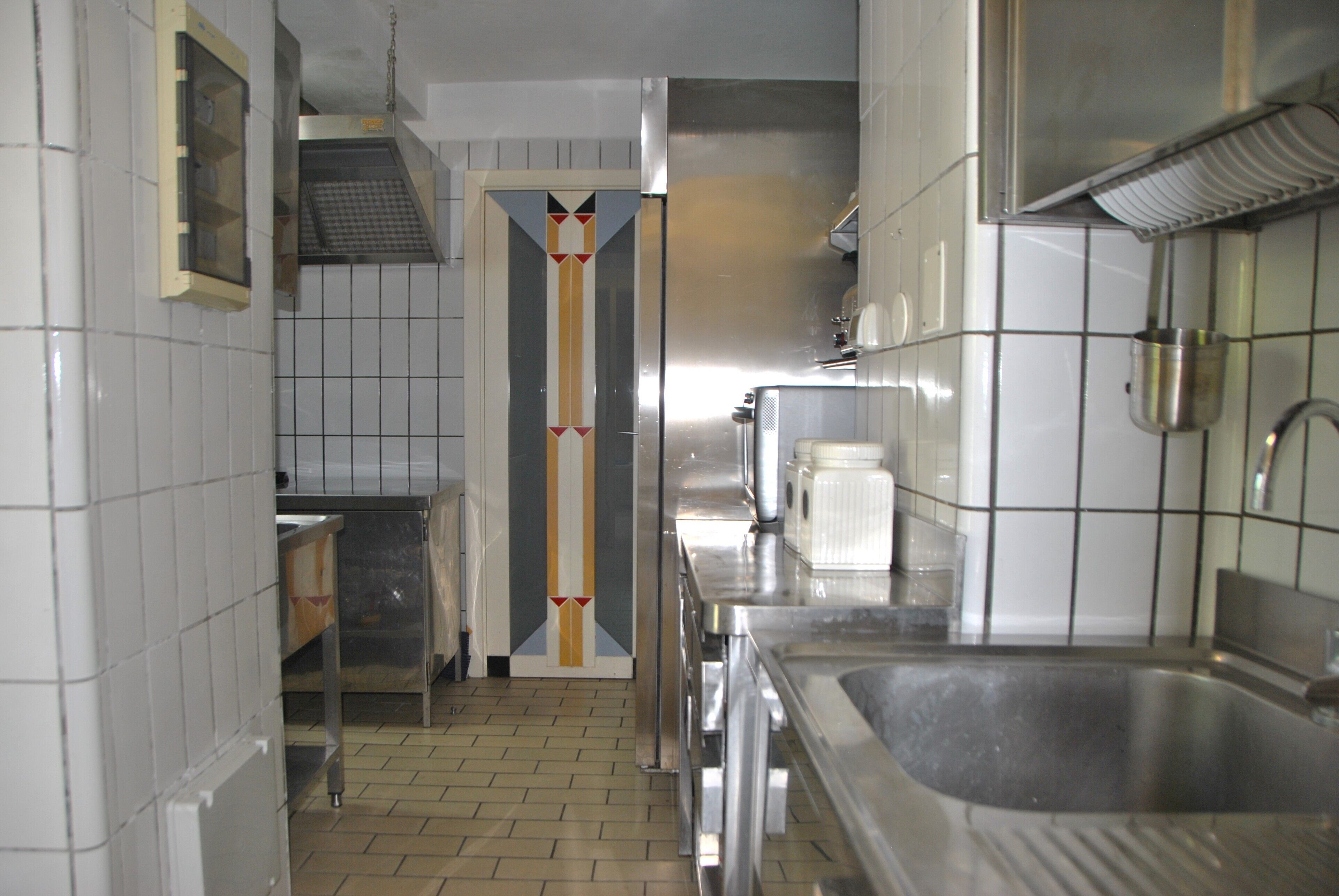 A kitchen with stainless steel appliances, a tiled backsplash, and a tiled floor.