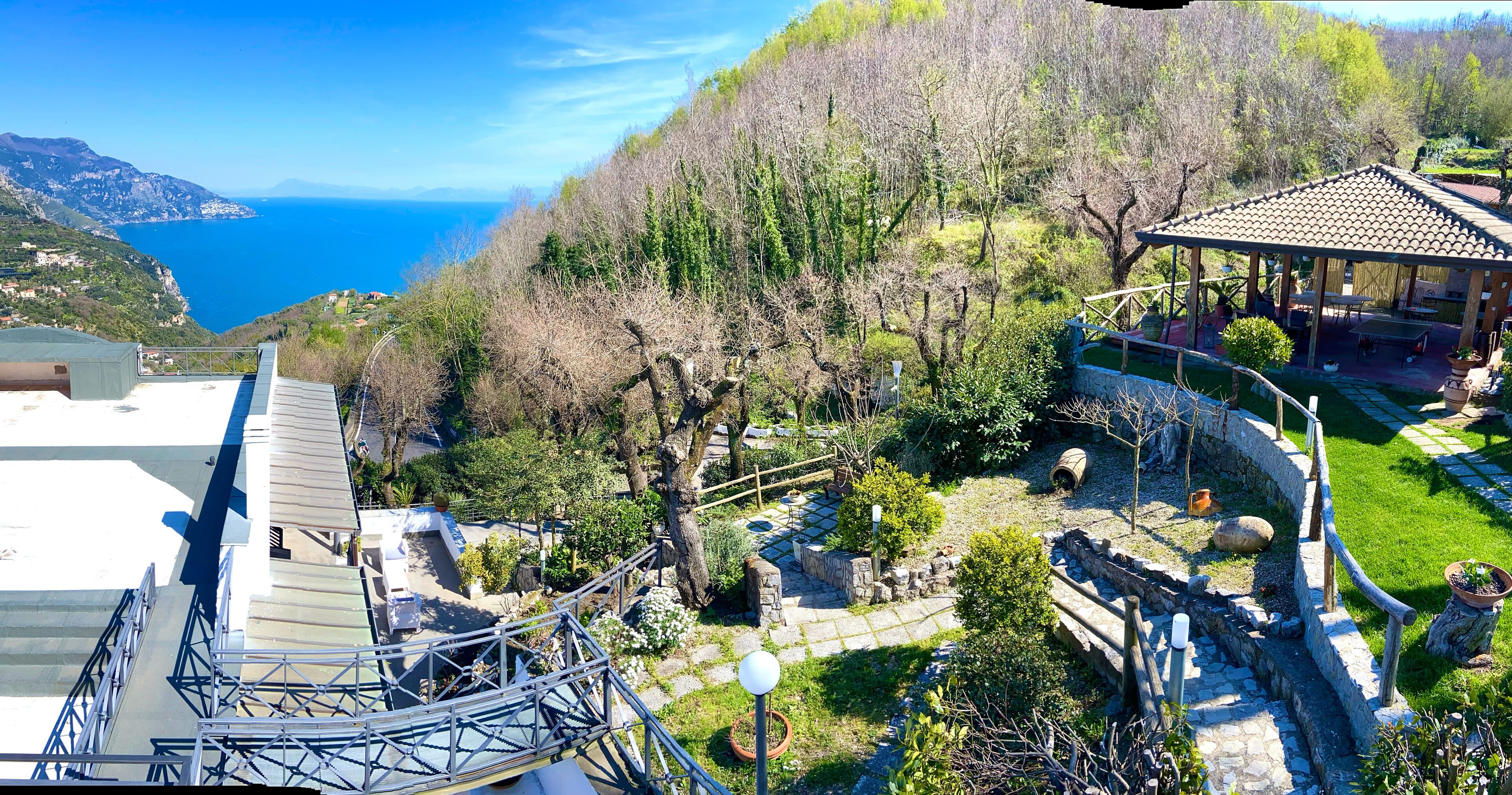 Un jardín con un pabellón, senderos de piedra y vistas al mar.