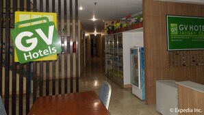 A hotel reception area with a reception desk, a counter with a computer, and a sign for GV Hotels. - GV Hotels Talisay City (Talisay)