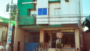 A multi-story building with a green and white facade, a visible 'GV' sign, and a ground-level entrance with a staircase. - GV Hotels Talisay City (Talisay)