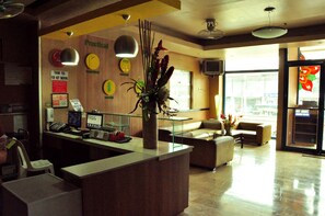 A reception area with a counter, a plant, a clock, and a sign indicating a shower.