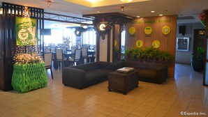 A hotel lobby with a reception desk, seating area, and a wall labeled 'Practical Budget Rooms'. - GV Tower Hotel (Cebu City)
