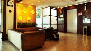 A lobby with a reception desk, seating area, and a wall with emergency instructions. - GV Tower Hotel (Cebu City)