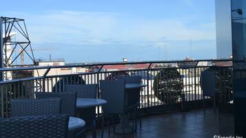 A rooftop terrace with wicker furniture and a view of the city skyline.