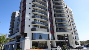 A multi-story hotel with balconies, a gaming store, and a parking area. - Springwood Tower Apartment Hotel (Springwood)