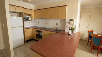 A kitchen with wooden cabinets, a refrigerator, a microwave, a sink, and a dining area with chairs and a table.
