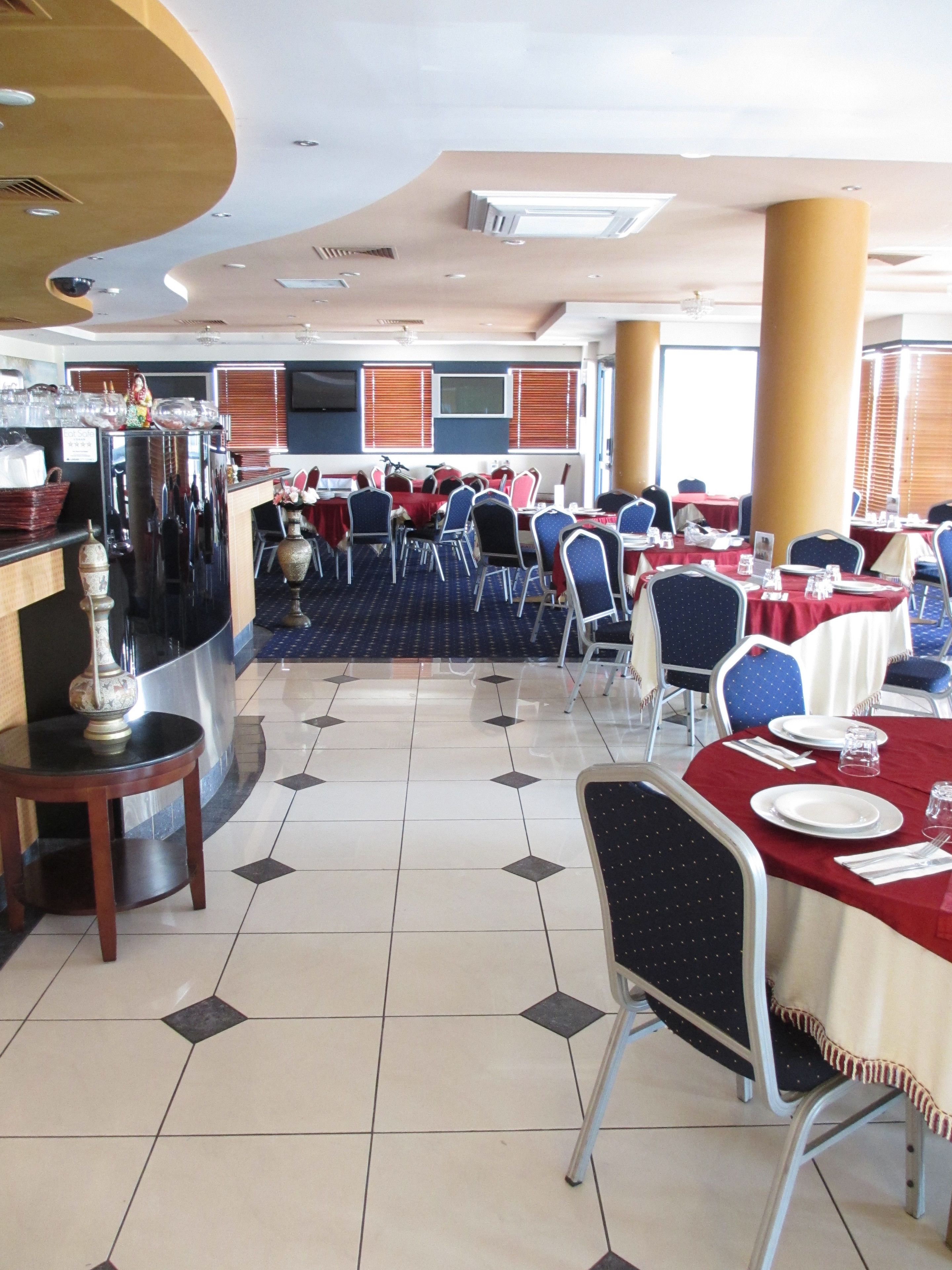 A restaurant with round tables, chairs, and a bar area.