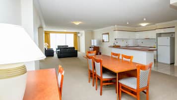 Una habitación de hotel moderna con comedor, kitchenette y sala de estar con sofá y televisor.