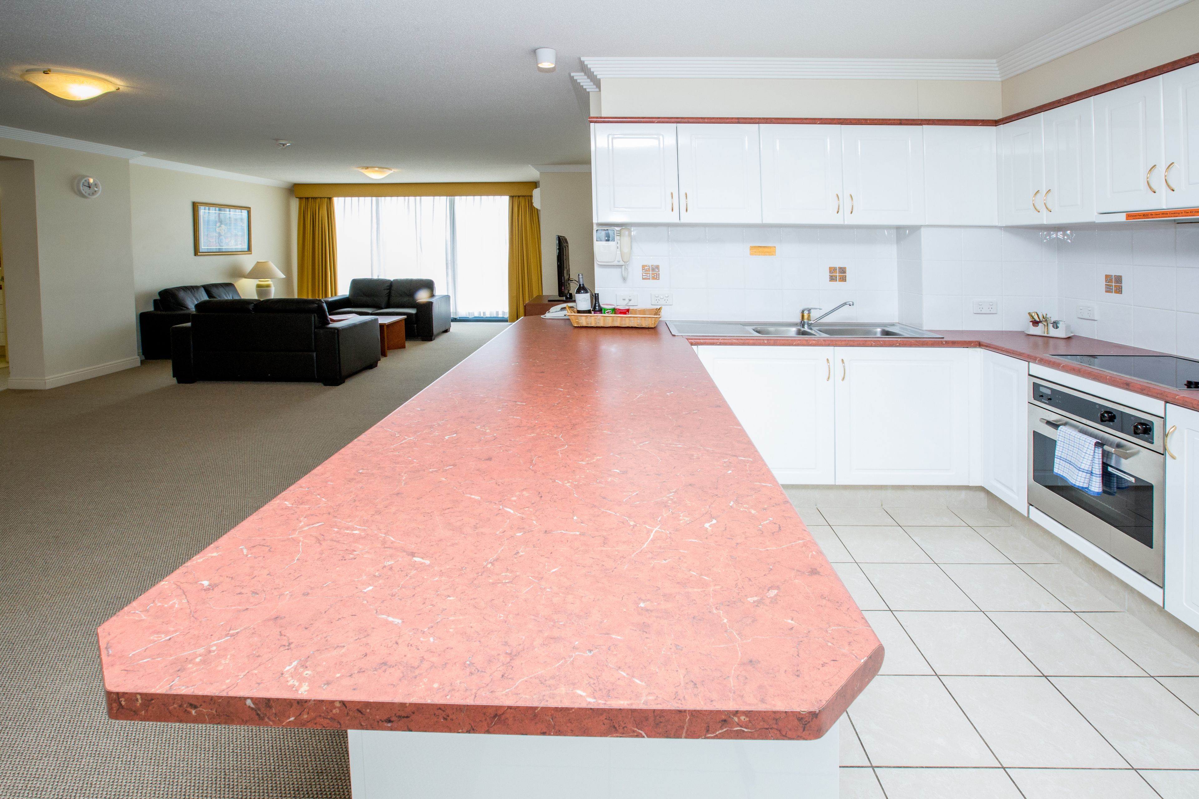 Una cocina moderna con armarios blancos, encimera de mármol y un comedor con sofá y mesa de centro.