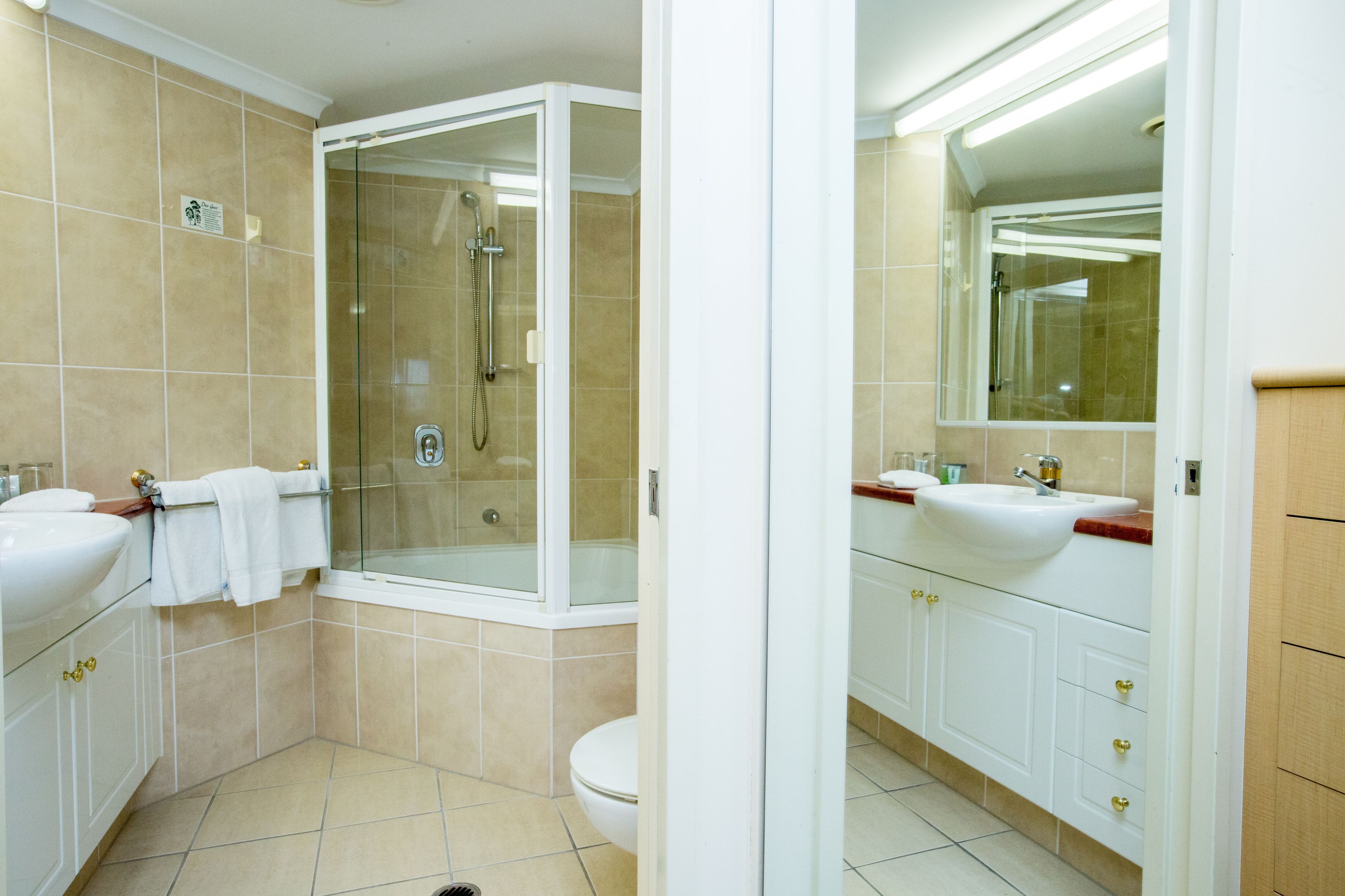 Ein modernes Badezimmer mit zwei Waschbecken, einer Duschkabine und einer Toilette.