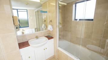 A modern bathroom with a large sink, a glass-enclosed shower, and a mirror above the sink.