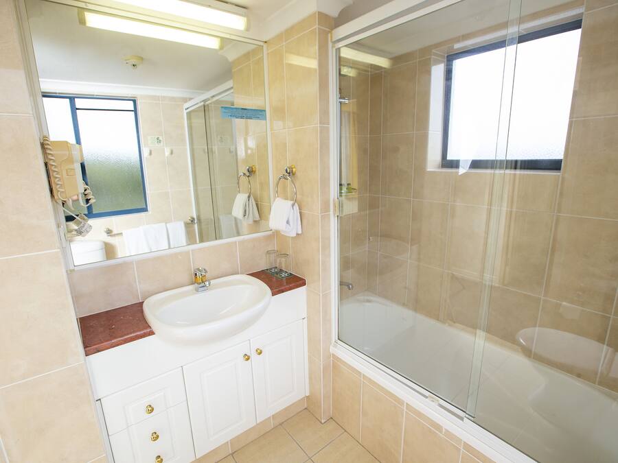 A modern bathroom with a large sink, a glass-enclosed shower, and a mirror above the sink.