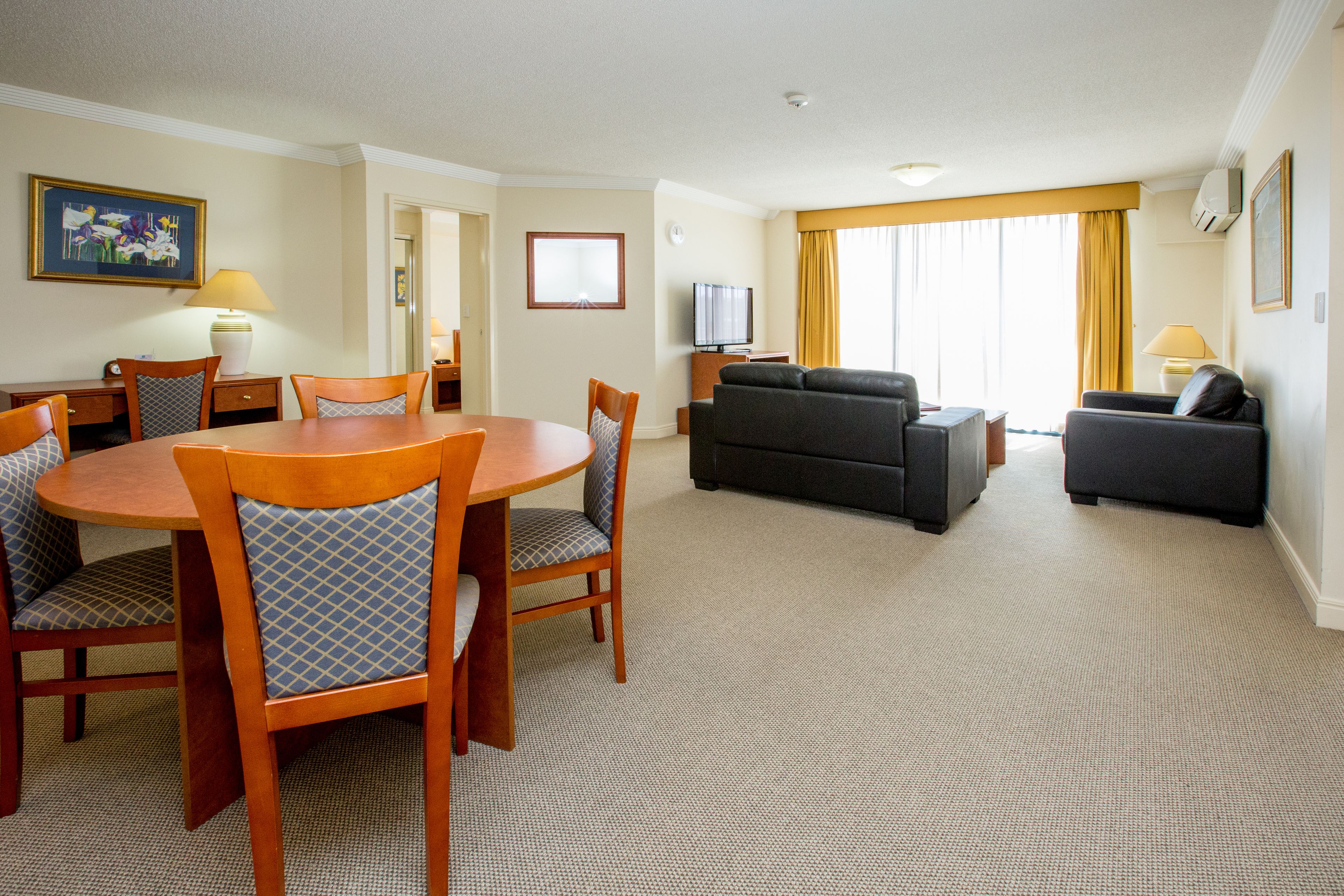 A hotel room with a dining area, a sofa, and a TV.