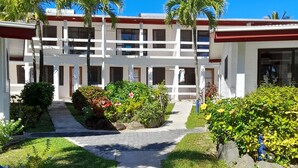 A hotel with a central courtyard, surrounded by lush greenery and palm trees.