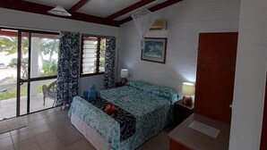 A room with a bed, a ceiling fan, a window with curtains, a wall-mounted air conditioner, and a door.