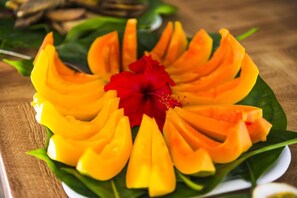 A plate of sliced mango arranged in a flower-like pattern with a red flower in the center. - Rumours Luxury Villas & Spa (Rarotonga)