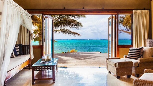 A room with a view of the ocean, a sofa, a coffee table, and wicker chairs. - Rumours Luxury Villas & Spa (Rarotonga)