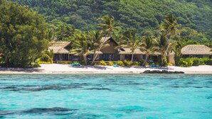 A beachfront resort with thatched-roof buildings, palm trees, and a sandy beach. - Rumours Luxury Villas & Spa (Rarotonga)
