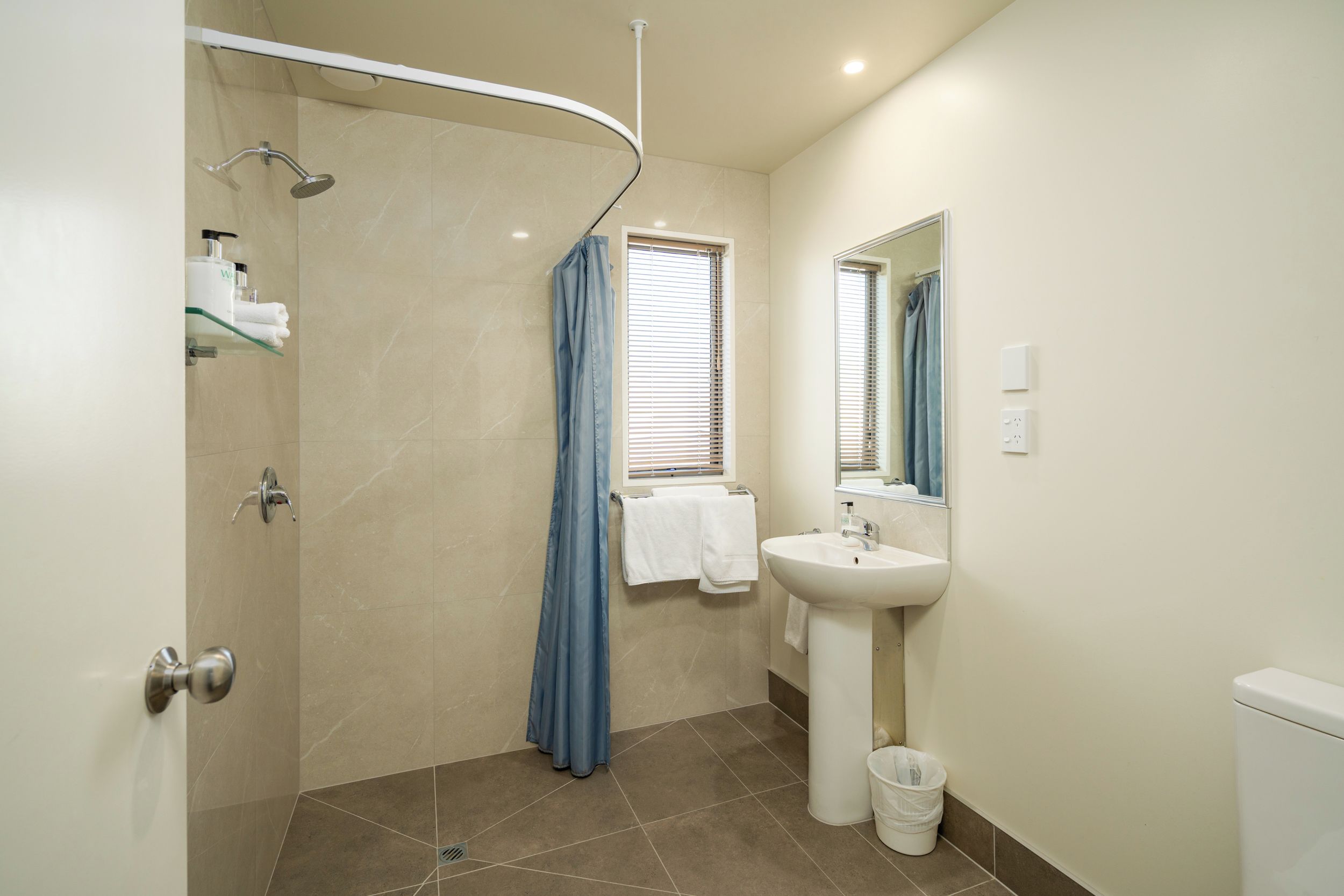 A modern bathroom with a shower, a sink, and a mirror.
