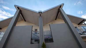 Een modern gebouw met een plat dak, twee zichtbare ramen met metalen tralies en een centrale verticale constructie.