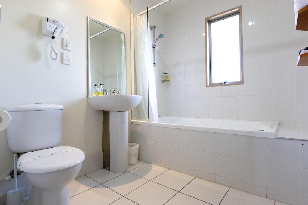 Et badeværelse med toilet, vask og bruser.