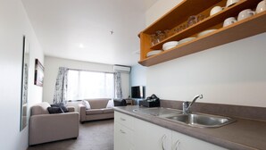 Een knus woongedeelte met een kitchenette, een bank en een televisie.
