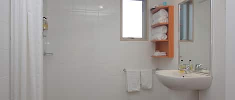 A bathroom with a shower, a sink, and a towel rack.