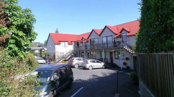 A row of two-story buildings with red roofs, parked cars, and a street lamp. - Owens Motel (Dunedin)