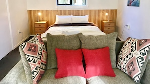 A bedroom with a bed, bedside tables, a window, and a wall-mounted painting. - Owens Motel (Dunedin)