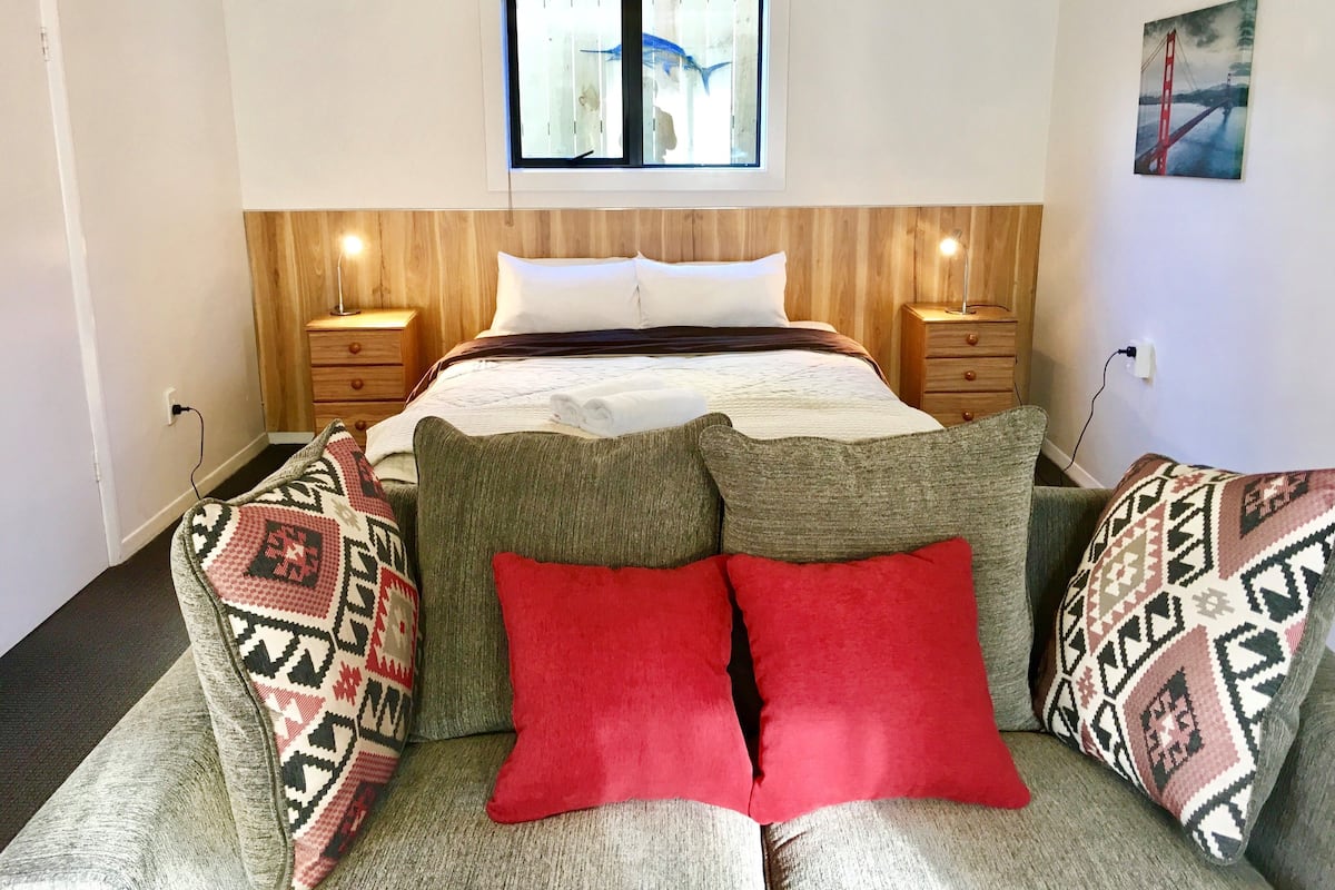 A bedroom with a bed, bedside tables, a window, and a wall-mounted painting.