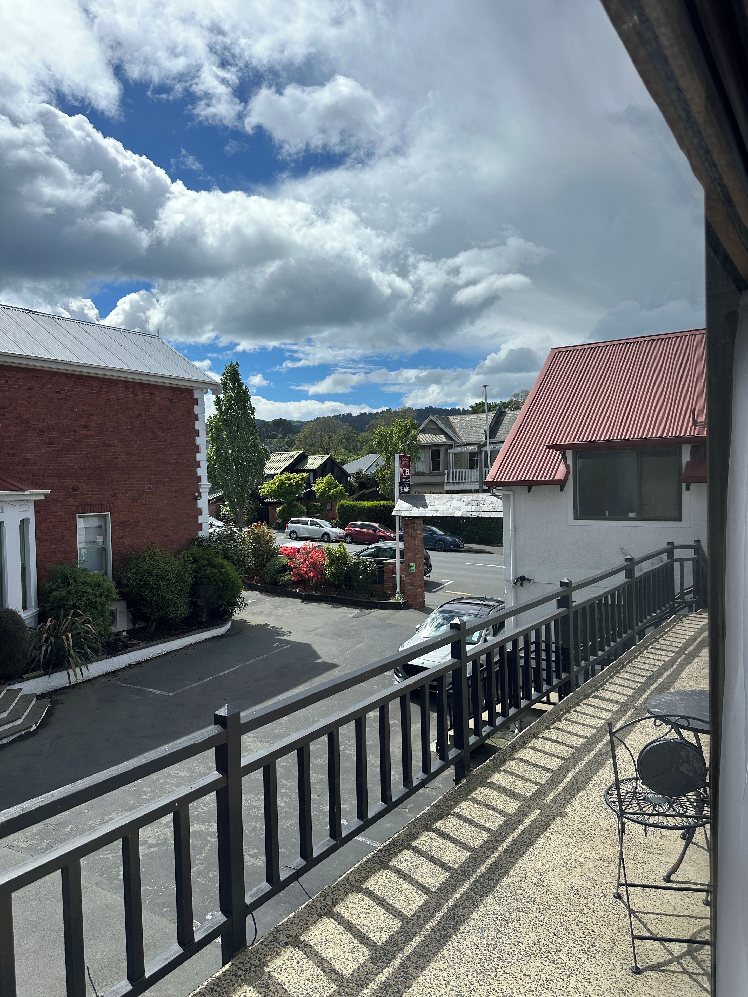 A hotel with a parking lot, a fenced balcony, and a view of the surrounding area.