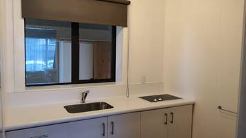 A kitchen with a window, sink, and cabinets.