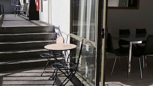 A hotel patio with outdoor seating, a staircase leading to the entrance, and a glass door entrance. - Owens Motel (Dunedin)