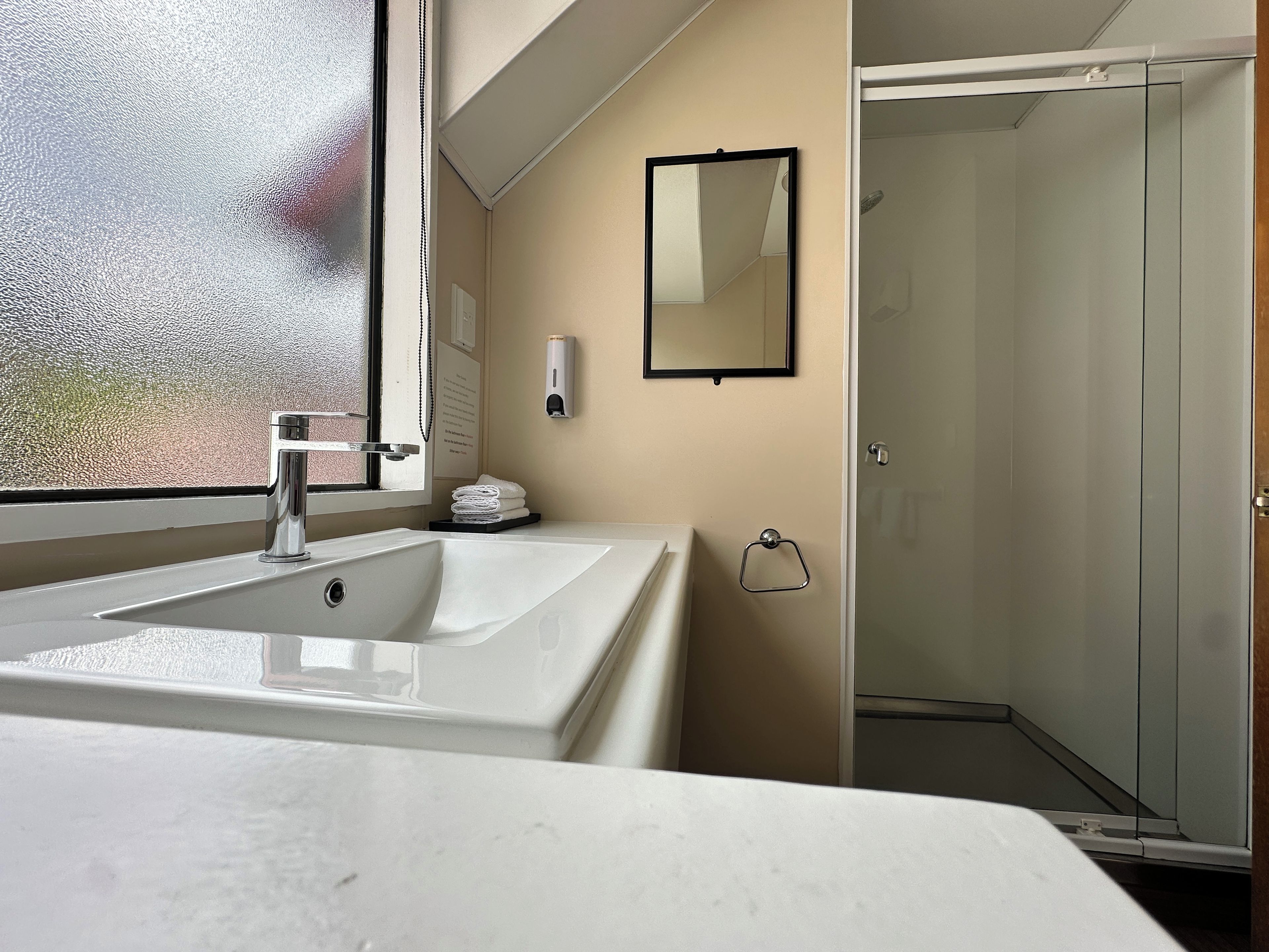 A bathroom with a white sink, a mirror, and a glass shower enclosure.