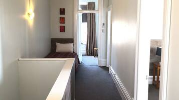 A hotel room with a bed, a desk, a chair, and a window.