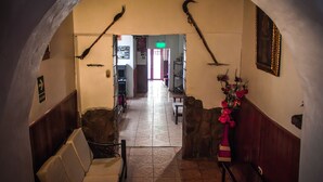 An arched hallway with a stone bench, a wooden chair, and a wall-mounted mirror. - San Blas Plaza Inn (Cusco)