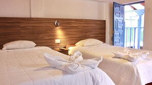 A hotel room with two beds, wooden headboard, white bedding, and a nightstand with a lamp. - San Blas Plaza Inn (Cusco)