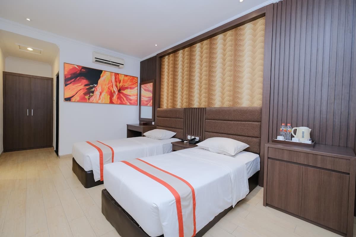 Een hotelkamer met twee bedden, een grote spiegel, een airconditioning en een houten garderobe.