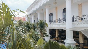 A building with a covered outdoor area featuring columns and a balcony with ornate railings. - The GRAND PALACE Hotel - YOGYAKARTA (Yogyakarta)