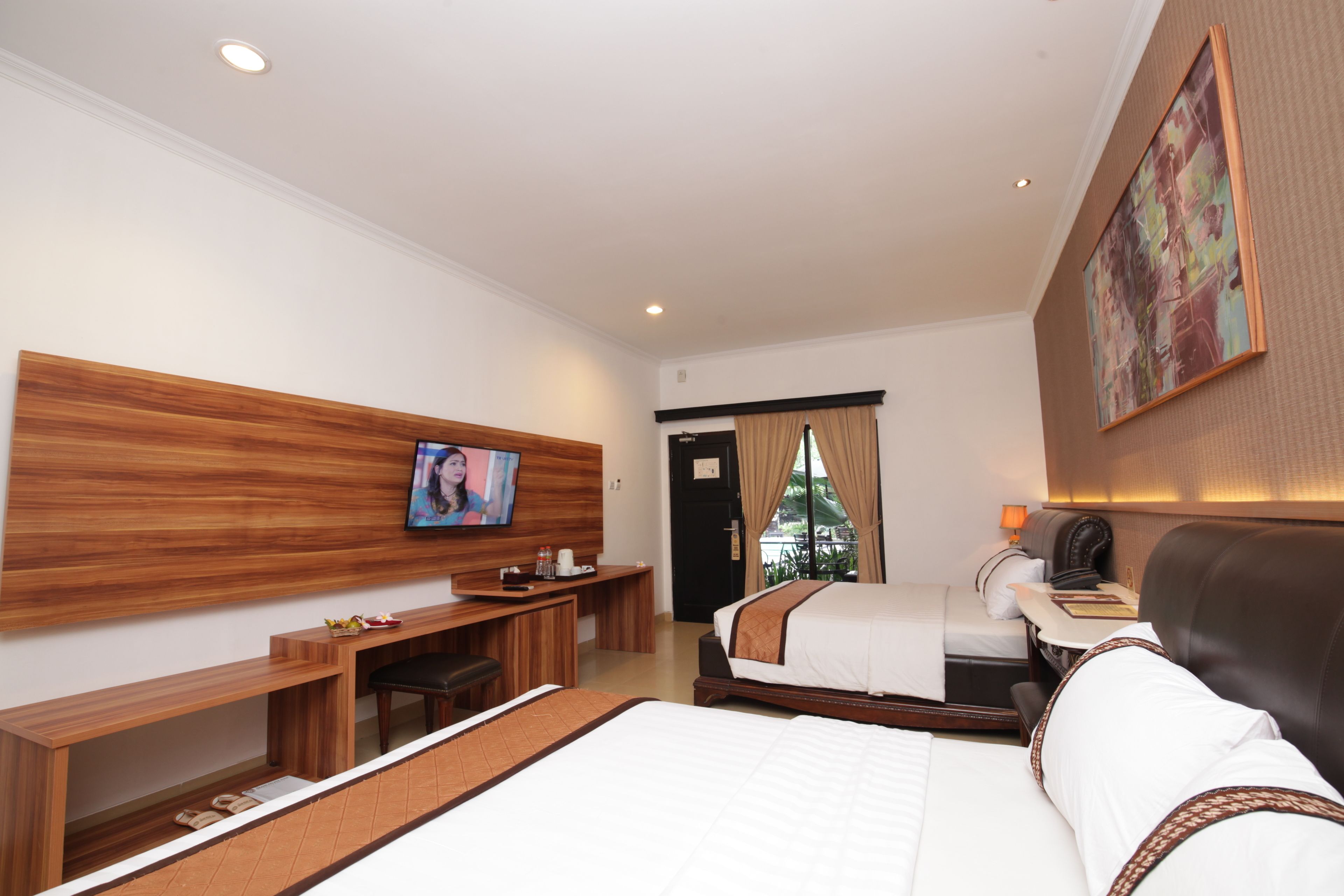 Habitación de hotel con una cama grande, un escritorio, un televisor y un cuadro en la pared.