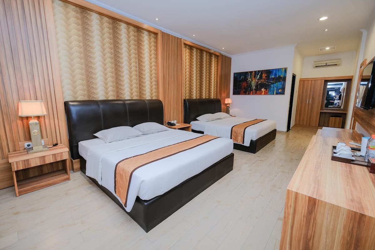 Een hotelkamer met twee bedden, een houten bureau, een schilderij aan de muur en een kledingkast.