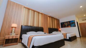 Una habitación de hotel con una cama grande, dos mesitas de noche, un cuadro en la pared y un equipo de aire acondicionado.