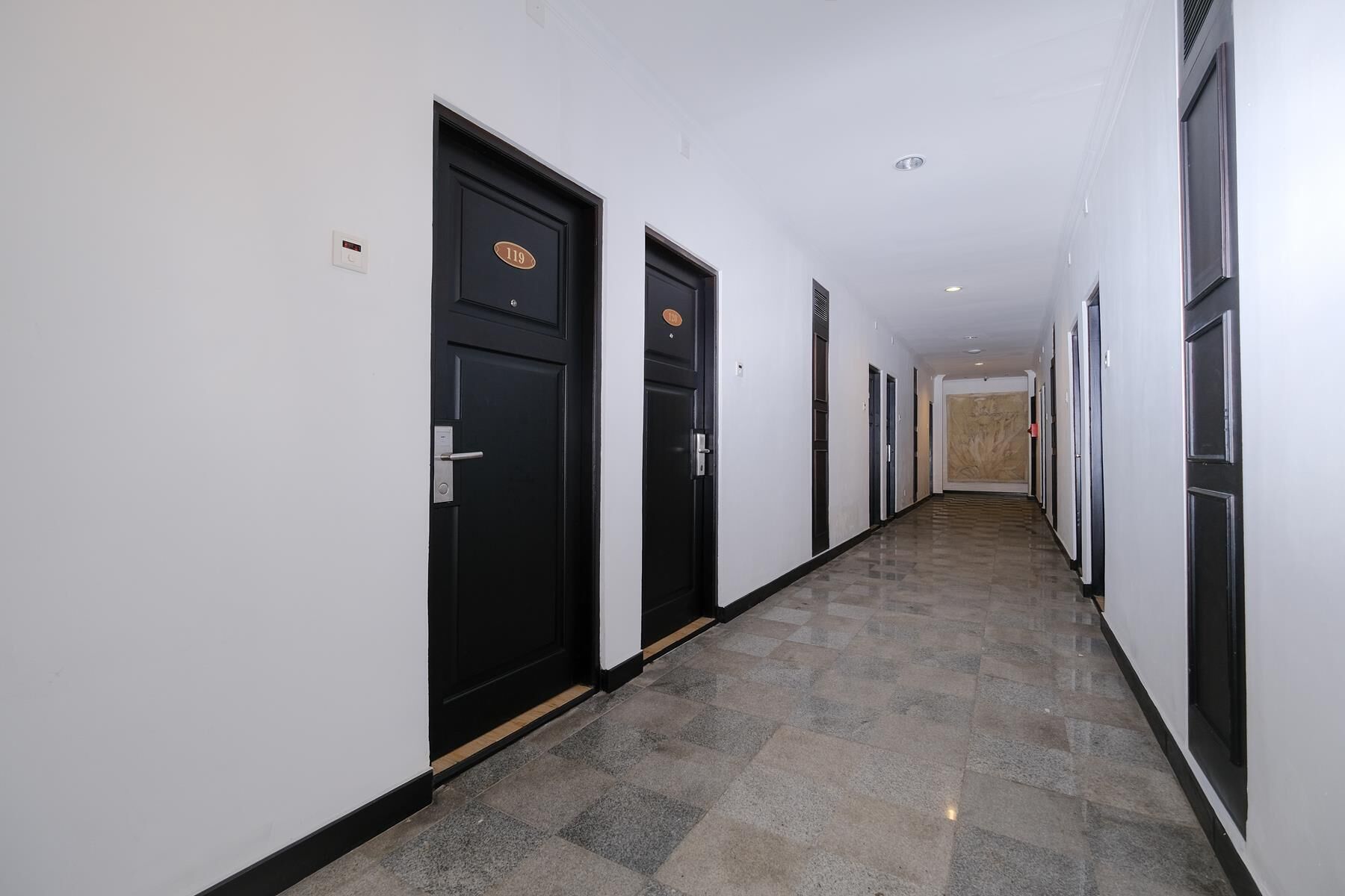 Un pasillo con puertas negras, cada una con un número.